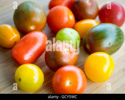 Une belle gamme de couleurs, des variétés de tomates d'été sur une surface de bambou. Banque D'Images