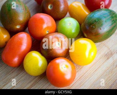 Une belle gamme de couleurs, des variétés de tomates d'été sur une surface de bambou. Banque D'Images