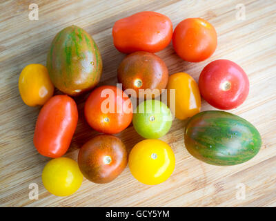 Une belle gamme de couleurs, des variétés de tomates d'été sur une surface de bambou. Banque D'Images