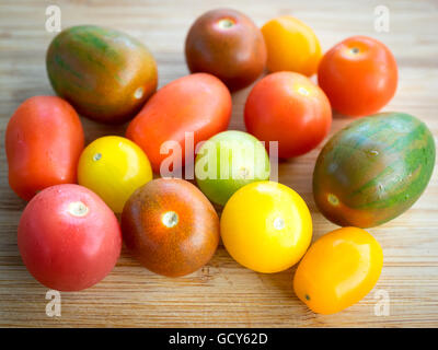 Une belle gamme de couleurs, des variétés de tomates d'été sur une surface de bambou. Banque D'Images