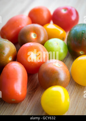 Une belle gamme de couleurs, des variétés de tomates d'été sur une surface de bambou. Banque D'Images