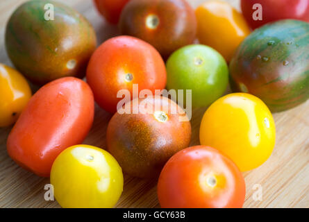 Une belle gamme de couleurs, des variétés de tomates d'été sur une surface de bambou. Banque D'Images