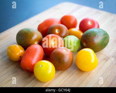 Une belle gamme de couleurs, des variétés de tomates d'été sur une surface de bambou. Banque D'Images