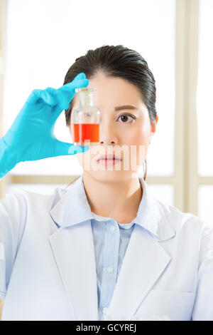 Female scientist bravant nouvelles frontières médicales bouteille avec un liquide rouge Banque D'Images