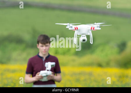 Teenage boy l'exploitation d'un drone quadcopter en campagne, UK. Banque D'Images