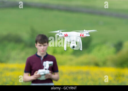 Teenage boy l'exploitation d'un drone quadcopter en campagne, UK. Banque D'Images