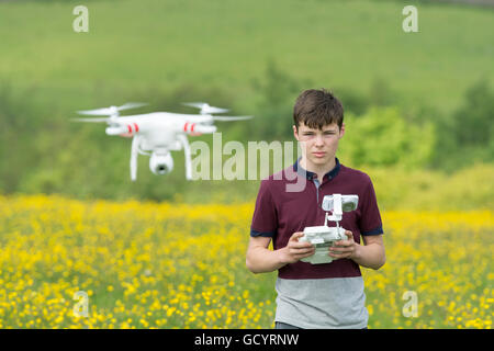 Teenage boy l'exploitation d'un drone quadcopter en campagne, UK. Banque D'Images