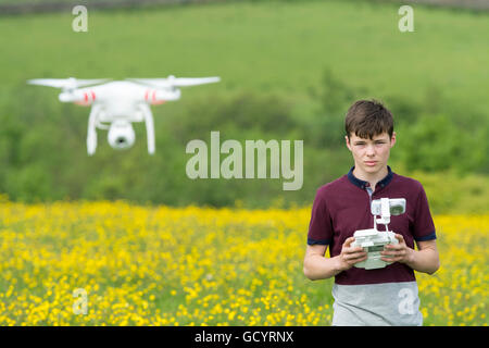 Teenage boy l'exploitation d'un drone quadcopter en campagne, UK. Banque D'Images