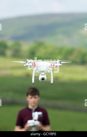 Teenage boy l'exploitation d'un drone quadcopter en campagne, UK. Banque D'Images