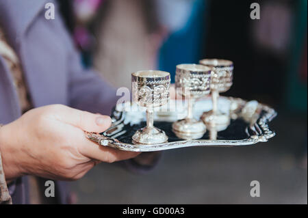 Verres à vin en argent sur une plaque d'argent dans la main. ensemble de tasses en métal sur un plateau Banque D'Images