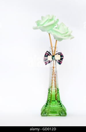 Deux roses décoratif vert vase en verre, sur fond blanc avec un ruban Banque D'Images