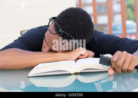 Closeup portrait nerdy, jeune homme dans de grandes lunettes noires holding watch, relevant très fatigué de la lecture, l'endormi, isolé outdo Banque D'Images