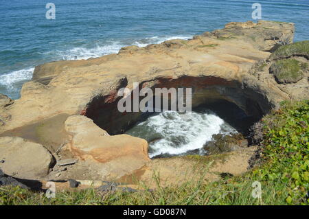 Le Devil's Punch Bowl près de Newport Oregon comme les vagues en rouleaux à travers les deux grottes marines. Banque D'Images