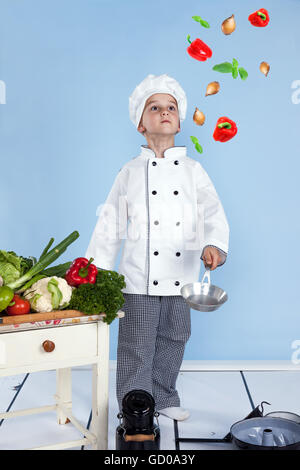 Jeune chef et son jonglant avec des légumes dans une casserole Banque D'Images