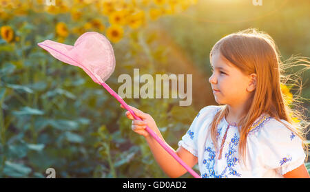 Petite fille joyeuse jouant dans un champ avec des insectes en soirée d'été Banque D'Images