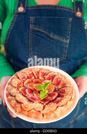 Des fig pie avec les noix et le miel dans les mains d'une femme Banque D'Images