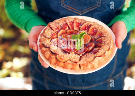 Des fig pie avec les noix et le miel dans les mains d'une femme Banque D'Images