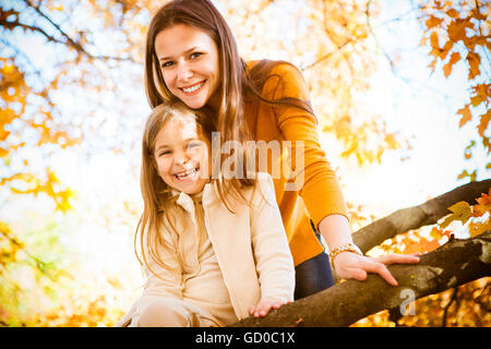 Deux soeurs joyeux jouant dans le parc en automne chaud jour Banque D'Images