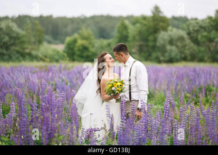 Happy wedding couple hugging in le champ lupin Banque D'Images