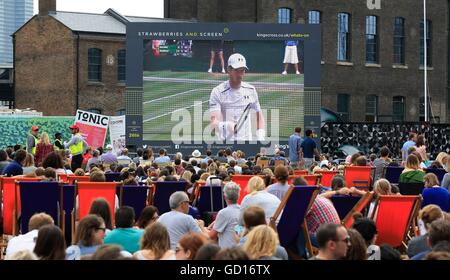 Les membres du public regarder la finale hommes entre Andy Murray et Milos Raonic, sur treize jours du tournoi de Wimbledon qui s'est tenue à l'All England Lawn Tennis et croquet Club à Wimbledon, sur un grand écran à la place du grenier, de Kings Cross, Londres. Banque D'Images