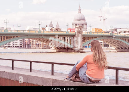 Jeune fille s'assit au bord de la Tamise avec vue sur la Cathédrale St Paul à Londres, Royaume-Uni Banque D'Images