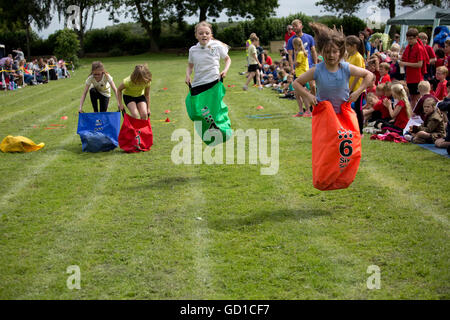 Les filles en compétition dans la course sac de sport à l'école primaire St James à Chipping Campden jour UK Banque D'Images