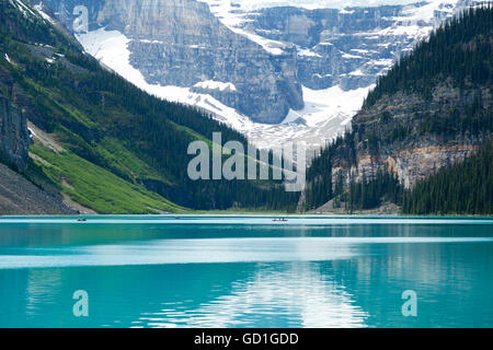 Les gens de l'aviron sur canoës à Lake Louise en Alberta, Canada. Les eaux d'été sont toujours et les montagnes en arrière-plan en font un site populaire. Banque D'Images