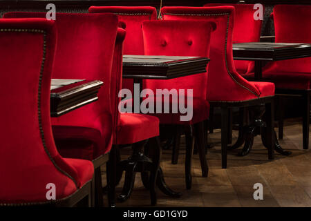 Chaises en velours rouge et des tables noires Banque D'Images