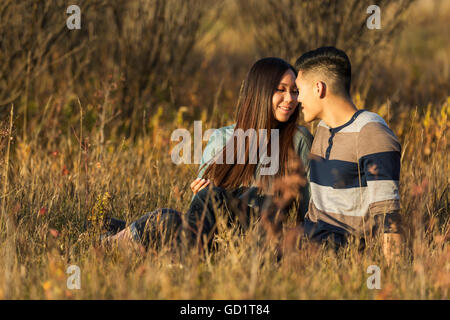 Un jeune couple asiatique bénéficiant du temps de qualité ensemble en plein air dans un parc en automne dans la chaleur de la lumière du soleil en début de soirée Banque D'Images