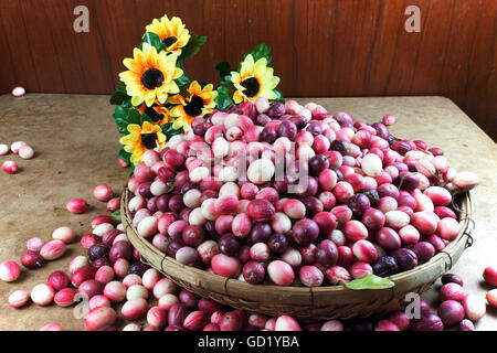 Fruit Karonda Carunda ou dans le panier sur la table. Ornée de tournesols artificiels. Banque D'Images