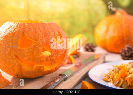 Sculpture d'un Jack O'Lantern sur une table d'extérieur rustique en automne. Banque D'Images