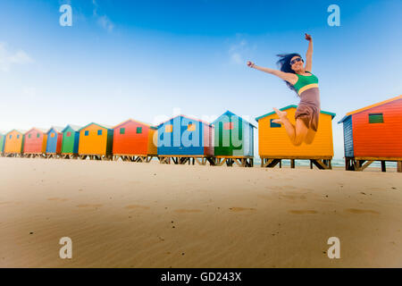 Laura Grier de sauter devant cabines colorées, Muizenberg Beach, Cape Town, Afrique du Sud, l'Afrique Banque D'Images