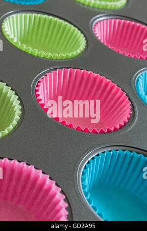 Cake ou muffin tin avec du papier coloré cas utile pour les concepts de cuisson Banque D'Images