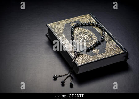 Livre de l'islam Coran et perles sur fond noir Banque D'Images