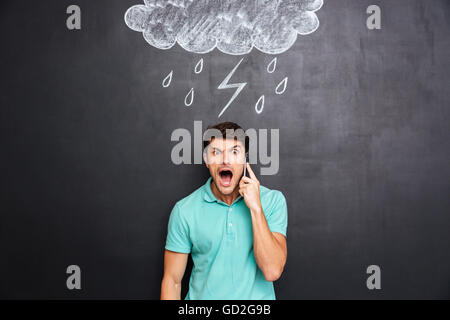 L'homme agressif et en colère en criant de standing avec tableau noir derrière lui Banque D'Images