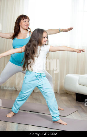 Concept de vie sain de la famille. La grossesse le yoga et la remise en forme. Heureux les jeunes femmes enceintes yoga maman travailler dehors avec ma petite fille Banque D'Images