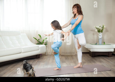 Concept de vie sain de la famille. La grossesse le yoga et la remise en forme. Heureux les jeunes femmes enceintes yoga maman l'élaboration avec petit enfant fille Banque D'Images