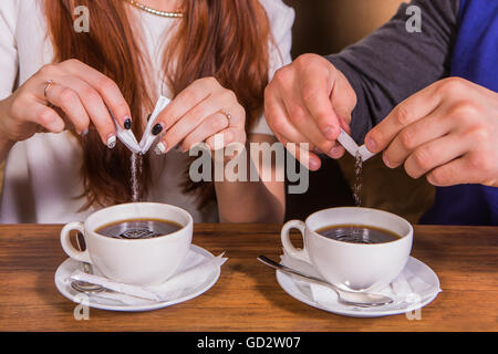 Mains d'une femme et un homme de mettre le sucre dans une tasse. Banque D'Images
