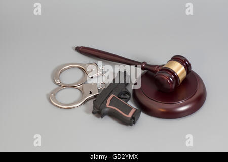 Judge's gavel, pistolet et menottes isolé sur fond gris Banque D'Images