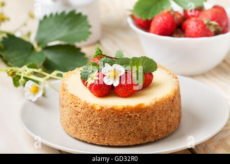 Cheesecake aux fraises sur une assiette, un bol de fraises sur un fond de bois Banque D'Images