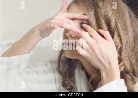 Belle jeune fille met des lentilles de contact. Banque D'Images