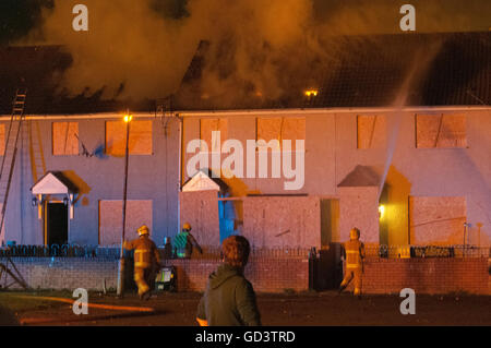 Belfast, Irlande du Nord. 09 mai 2016 - L'Irlande du Nord Service d'incendie et de sauvetage de former un certain nombre de tuyaux sur les toits d'une rangée de maisons mitoyennes après deux maisons ont été incendiés par les 'traditionnels' 11e Nuit de joie. Crédit : Stephen Barnes/Alamy Live News Banque D'Images