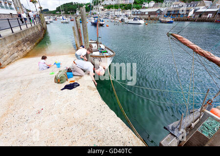 Un homme et les jeunes enfants garçon et fille du crabe ou en crabe sur la cale de halage à la populaire station balnéaire de Cornouailles looe en été, Cornwall, England, UK Banque D'Images