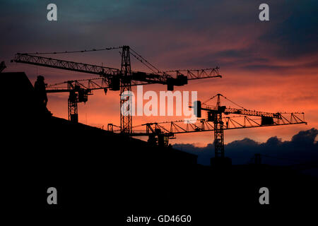 Berlin, Allemagne. 12 juillet, 2016. Nuages rouges peut être vu derrière les grues à Berlin, Allemagne, 12 juillet 2016. Photo : Maurizio Gambarini/DPA - PAS DE FIL - SERVICE/dpa/Alamy Live News Banque D'Images