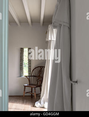 Fauteuil en bois au coin de la chambre avec des rideaux en lin blanc Banque D'Images