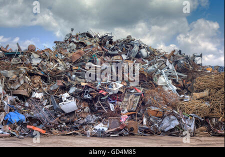 Le recyclage des matières premières en fer plus pieux ciel nuageux. Déchets métalliques Junkyard Banque D'Images