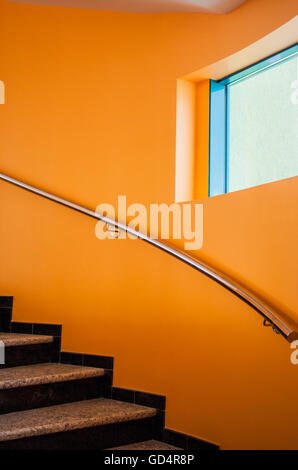 Escalier incurvé dans un luxueux immeuble de bureaux à côté d'un mur orange Banque D'Images