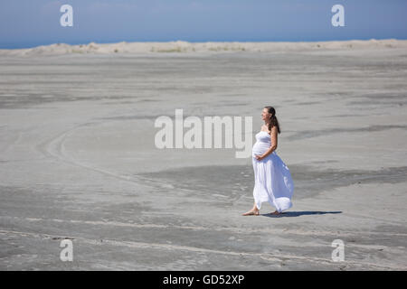 La femme enceinte marche sur la plage à l'heure d'été Banque D'Images
