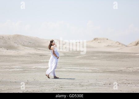 La femme enceinte marche sur la plage à l'heure d'été Banque D'Images