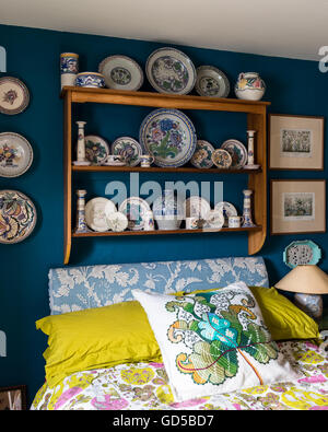 Poole pottery affichée sur planche en bois dans la chambre peinte en bleu l'espace profond à peu Greene.Le lit est recouvert et couvercle Banque D'Images